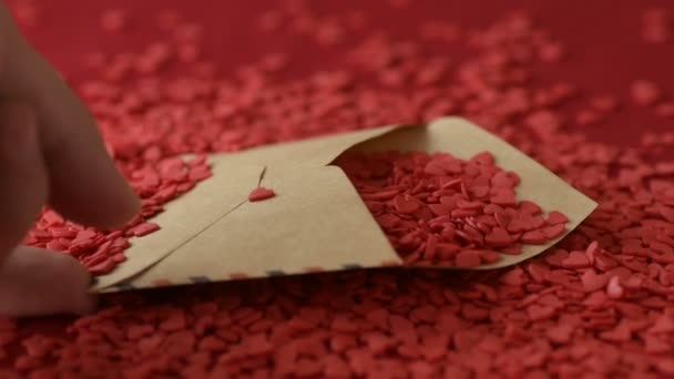 Scarlet Hartvormige Suiker Confetti Vallen Uit Valentijn Wenskaart Rode Achtergrond — Stockvideo