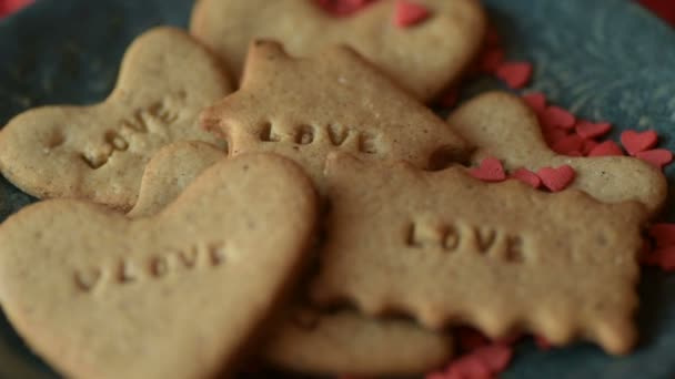 红红的心形状的糖圆饼碎了 落在饼干上 上面写着爱的字 浪漫的爱情 爱心的情人节 母亲节 婚纱设计理念 — 图库视频影像