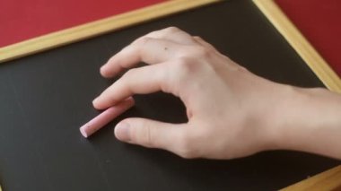 Kız ya da genç bir kadının eli tahtaya pembe tebeşirle kalp hatları çizer. Romantik aşk, sevgi dolu Sevgililer Günü, Anneler Günü, düğün hazırlığı tasarım konsepti.