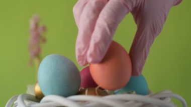 Pembe, altın ve yeşil renkte renkli Paskalya yumurtaları pembe ve mor sümbül çiçekleriyle bulanık yeşil arka planda dönen samanların üzerinde yatar. Bahar Hıristiyan bayramı tasarım konsepti