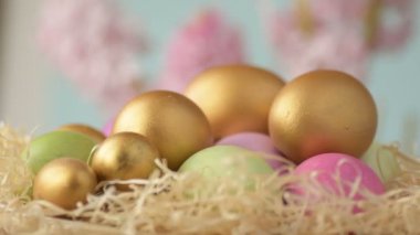 Pembe, altın ve yeşil renkte renkli Paskalya yumurtaları pembe ve mor sümbül çiçekleriyle bulanık yeşil arka planda dönen samanların üzerinde yatar. Bahar Hıristiyan bayramı tasarım konsepti