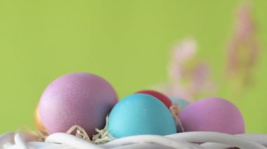 Pembe, altın ve yeşil renkte renkli Paskalya yumurtaları pembe ve mor sümbül çiçekleriyle bulanık yeşil arka planda dönen samanların üzerinde yatar. Bahar Hıristiyan bayramı tasarım konsepti