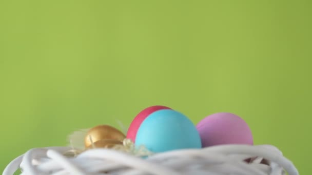 五彩缤纷的粉色 金色和绿色复活节彩蛋躺在稻草上 在模糊的浅绿色背景上旋转着 粉色和洋红色的风信子花 春季基督教节假日设计理念 — 图库视频影像