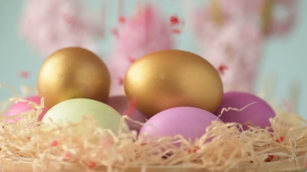 ピンク 緑の色のイースターの卵は ピンクとマゼンタのヒヤシンスの花とぼやけた薄緑色の背景に回ってわらに横たわっています 春キリスト教の休日のデザインコンセプト — ストック動画