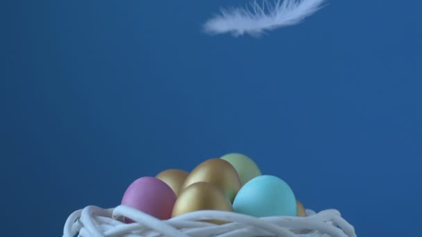 色鮮やかなイースターエッグに羽が落ちる ピンク 緑の色の色の卵は ぼやけた光緑の背景にあります 羽は上から落ちてくる 春キリスト教の休日のデザインコンセプト — ストック動画