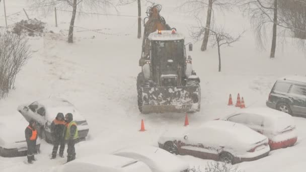 Ciągnik Czyszczący Ulice Między Domami Śniegu Podczas Śniegu Zamieci Śnieżnej — Wideo stockowe