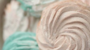Tatlı renkli ev yapımı pastel şekerlemeler nane yeşili, pembe ve krema renkleri seramik plaka üzerinde ağır çekimde dönüyor sarı arka planda şeker tozu serpiştiriliyor. Yukarıdan görüntüle