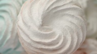 Tatlı renkli ev yapımı pastel şekerlemeler nane yeşili, pembe ve krema renkleri seramik plaka üzerinde ağır çekimde dönüyor sarı arka planda şeker tozu serpiştiriliyor. Ev yemeği. 
