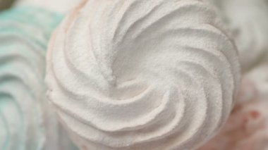 Tatlı renkli ev yapımı pastel şekerlemeler nane yeşili, pembe ve krema renkleri seramik plaka üzerinde ağır çekimde dönüyor sarı arka planda şeker tozu serpiştiriliyor. Ev yemeği. 