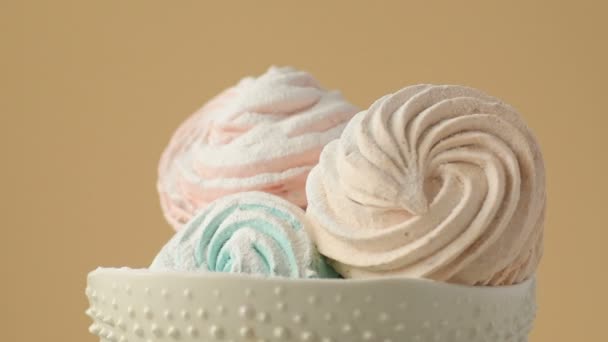 柔和的薄荷绿色 粉色和奶油色的甜彩色自制棉花糖在陶瓷盘上缓慢旋转 黄色背景上撒满糖粉 家庭烹饪 — 图库视频影像