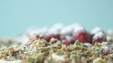 Ispanaklı ev yapımı vejetaryen pastası yavaşça dönen kızılcıkla süslenmiş ve mavi arka planda yavaş çekimde üzerine şeker tozu serpilmiş. Sağlıklı vejetaryen ve ev yapımı gıda konsepti