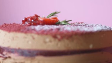 Nar, çilek, biberiye ve pudra şekerle süslenmiş Marsala çikolatalı kremalı pasta mavi arka planda yavaş çekimde döner. Pastanın güzel dokusu, makro fotoğrafçılık.