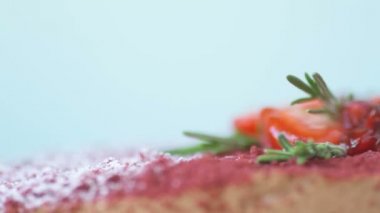 Nar, çilek, biberiye ve şeker tozu ile süslenmiş Marsala çikolatalı mus keki mavi arka planda döner. Güzel desenli pasta, üst manzara, makroyu kapat. Tatlı konsepti