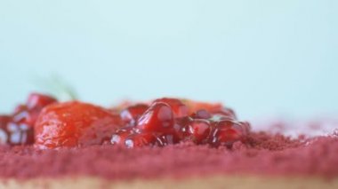 Nar, çilek, biberiye ve şeker tozu ile süslenmiş Marsala çikolatalı mus keki mavi arka planda döner. Güzel desenli pasta, üst manzara, makroyu kapat. Tatlı konsepti