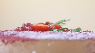 Nar, çilek, biberiye ve şeker tozu ile süslenmiş Marsala çikolatalı mus keki kahverengi arka planda döner. Güzel desenli pasta, üst manzara, makroyu kapat. Tatlı konsepti