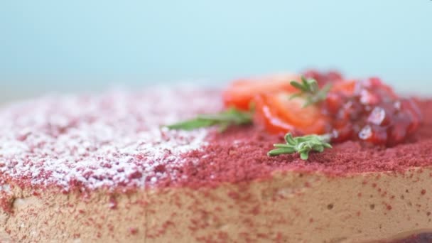 ザクロ イチゴ ローズマリー 粉砂糖で装飾されたマルサラチョコレートムースケーキは 青い背景にスローモーションで回転します ケーキの美しい質感 マクロ写真 — ストック動画