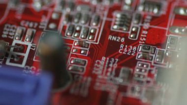 Çipleri ve mikro devreleri yavaş çekimde olan parlak kırmızı bir panelin döndürülmesi 