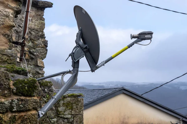 Kırsal bir köydeki eski bir taş ev duvarına uydu anteni yerleştirilmiş.