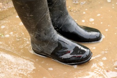 Siyah uzun kirli botlar su birikintisinde duruyor.