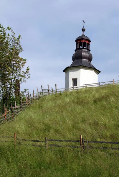 Çayırı ve yolu olan bir dağ manzarasında şapel.