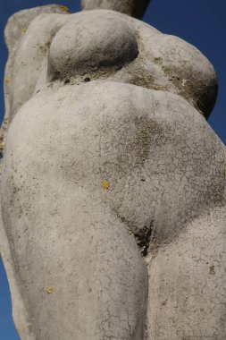 Mavi gökyüzü olan çıplak bir kadın heykeli.