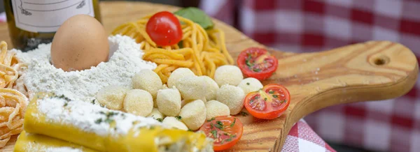 Pasta and tomato on chopping board — Stock Photo, Image