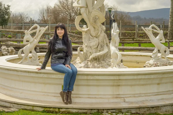 Mädchen sitzt auf Brunnen — Stockfoto