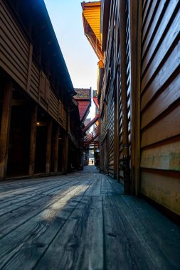 Ahşap bir caddenin altından bak. Bryggen, Bergen, Norveç 'te dar bir caddenin dikey fotoğrafı. Tarihi Hanseatik renkli ahşap binalar, güneşli bir gün, rahat bir ortaçağ atmosferi.