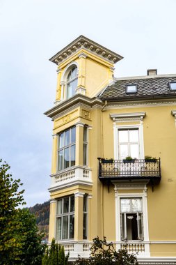 Norveç 'in Bergen kentinde zarif giriş pencereleri (erkers) olan güzel açık sarı tarihi bina. Çekici detayları olan klasik İskandinav mimarisi, aydınlık bir günde çekildi..