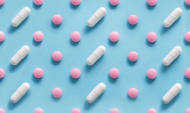 Mavi arka planda dağılmış haplar, tıp konsepti. Uzun, yuvarlak, beyaz bir şapka ve mavi üzerine sert haplar. Mavi renkli hapların ve kapsüllerin deseni.