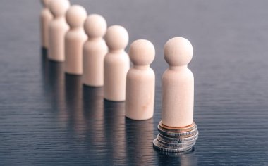 Bozuk para yığınının üzerinde duran minyatür tahta figürler. Eşitsizlik ve sosyal sınıf. Gelir ve ekonomik eşitsizlik kavramı. Sosyal sınıf, ideoloji ve sağlıkta eşitsizlik