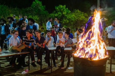 Hayfa, İsrail - 29 Nisan 2021: Ultra Ortodoks Yahudiler, Lag BaOmer bayramını ateşin etrafında toplanan çocuklarla kutluyor. Hayfa, İsrail