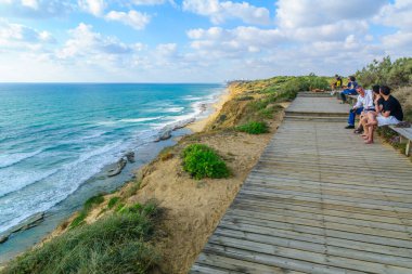 Arsuf, İsrail - 4 Haziran 2021: İsrail 'in Hof HaSharon Ulusal Parkı' ndaki kum taşı kayalıklarının ve Akdeniz kıyısının ziyaretçileri ile görüntüsü