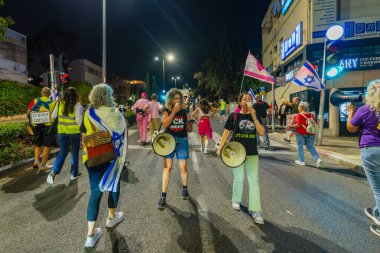 Hayfa, İsrail - 22 Kasım 2025: Çeşitli tabelaları ve bayrakları olan insanlar, ateşkes sonrasında hükümete karşı düzenlenen bir protesto mitingine katıldılar. Hayfa, İsrail