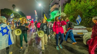 Hayfa, İsrail - 06 Aralık 2025: Çeşitli tabelaları ve bayrakları olan insanlar, ateşkes sonrasında hükümete karşı düzenlenen bir protesto mitingine katıldılar. Hayfa, İsrail