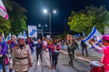 Hayfa, İsrail - 13 Aralık 2025: Çeşitli tabelaları ve bayrakları olan insanlar, hükümete karşı düzenlenen bir protesto mitingine katıldı, yeni polis gereksinimleri nedeniyle kaldırıma itildi. Hayfa, İsrail