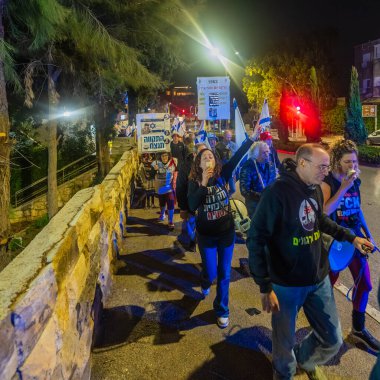 Hayfa, İsrail - 20 Aralık 2025: Çeşitli tabelaları ve bayrakları olan insanlar, hükümete karşı düzenlenen bir protesto mitingine katıldı, yeni polis gereksinimleri nedeniyle kaldırıma itildi. Hayfa, İsrail