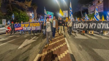 Hayfa, İsrail - 20 Aralık 2025: Çeşitli tabelaları ve bayrakları olan insanlar, ateşkes sonrasında hükümete karşı düzenlenen bir protesto mitingine katıldılar. Hayfa, İsrail