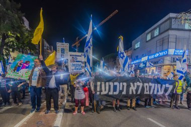Hayfa, İsrail - 20 Aralık 2025: Çeşitli tabelaları ve bayrakları olan insanlar, ateşkes sonrasında hükümete karşı düzenlenen bir protesto mitingine katıldılar. Hayfa, İsrail