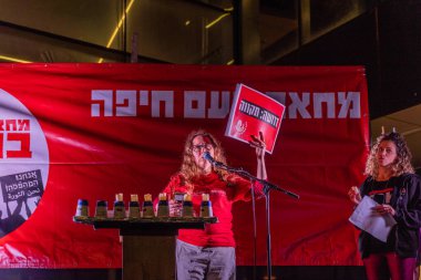 Hayfa, İsrail - 20 Aralık 2025: Aktivist, hükümete karşı ateşkesin ardından düzenlenen protesto mitinginin bir parçası olan Hanuka Menorah 'ın mumlarını yakıyor. Hayfa, İsrail