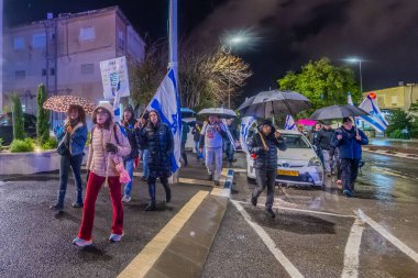 Hayfa, İsrail - 27 Aralık 2025: Çeşitli tabelaları ve bayrakları olan insanlar, hükümete karşı düzenlenen bir protesto mitingine katıldı, yeni polis gereksinimleri nedeniyle kaldırıma itildi. Hayfa, İsrail