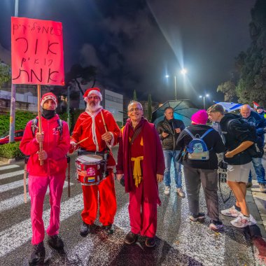 Hayfa, İsrail - 27 Aralık 2025: İnsanlar hükümete karşı bir protesto yürüyüşüne (Noel Baba gibi giyinmiş bir adamla birlikte) katılıyor. Hayfa, İsrail