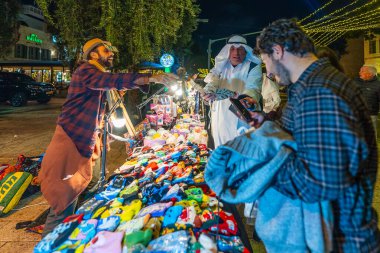 Hayfa, İsrail - 31 Aralık 2025: Katar Şeyhi gibi giyinmiş bir grup aktivist, Katar-kapısı yolsuzluk olayının sembolik bir protestosu olarak insanlara para dağıtıyor. Alman Kolonisi, Hayfa, İsrail