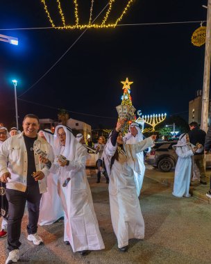 Hayfa, İsrail - 31 Aralık 2025: Katar Şeyhi gibi giyinmiş bir grup aktivist, Katar-kapısı yolsuzluk olayının sembolik bir protestosu olarak insanlara para dağıtıyor. Alman Kolonisi, Hayfa, İsrail