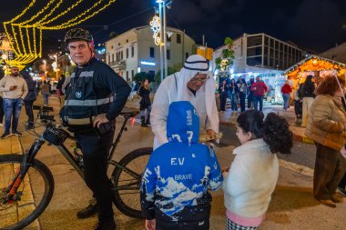 Hayfa, İsrail - 31 Aralık 2025: Katar Şeyhi gibi giyinmiş bir grup aktivist, Katar-kapısı yolsuzluk olayının sembolik bir protestosu olarak insanlara para dağıtıyor. Alman Kolonisi, Hayfa, İsrail