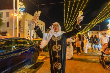 Hayfa, İsrail - 31 Aralık 2025: Katar Şeyhi gibi giyinmiş bir grup aktivist, Katar-kapısı yolsuzluk olayının sembolik bir protestosu olarak insanlara para dağıtıyor. Alman Kolonisi, Hayfa, İsrail
