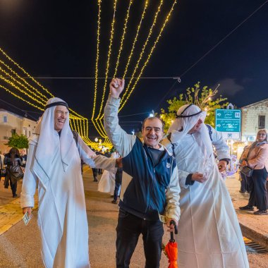 Hayfa, İsrail - 31 Aralık 2025: Katar Şeyhi gibi giyinmiş bir grup aktivist, Katar-kapısı yolsuzluk olayının sembolik bir protestosu olarak insanlara para dağıtıyor. Alman Kolonisi, Hayfa, İsrail