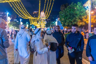 Hayfa, İsrail - 31 Aralık 2025: Katar Şeyhi gibi giyinmiş bir grup aktivist, Katar-kapısı yolsuzluk olayının sembolik bir protestosu olarak insanlara para dağıtıyor. Alman Kolonisi, Hayfa, İsrail