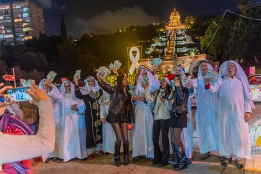 Hayfa, İsrail - 31 Aralık 2025: Katar Şeyhi gibi giyinmiş bir grup aktivist, Katar-kapısı yolsuzluk olayının sembolik bir protestosu olarak insanlara para dağıtıyor. Alman Kolonisi, Hayfa, İsrail