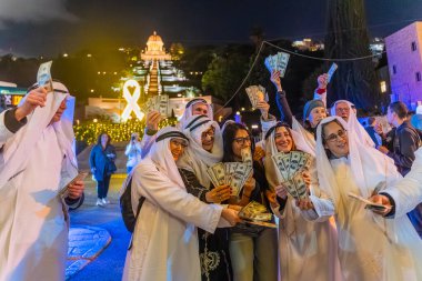 Hayfa, İsrail - 31 Aralık 2025: Katar Şeyhi gibi giyinmiş bir grup aktivist, Katar-kapısı yolsuzluk olayının sembolik bir protestosu olarak insanlara para dağıtıyor. Alman Kolonisi, Hayfa, İsrail